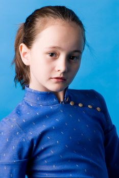 The girl of ten years in studio on a dark blue background, in the chinese dress.
