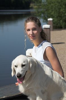 Pretty blond woman outdoors with her dog on a sunny day