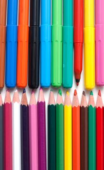 Crayons and soft-tip pens to rest upon white background