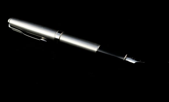 Isolated black and silver fountain point pen on black background