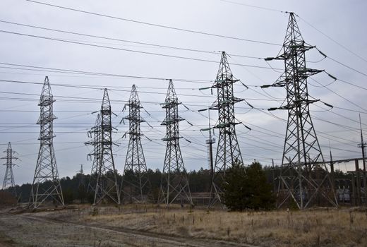 Power transmission towers in the autumn forest. Overcast sky.