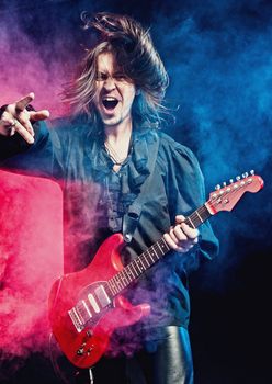 Rock-star perfoming loud music on red electric guitar
