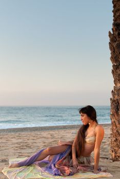 Oriental belly dancer posing on a beach