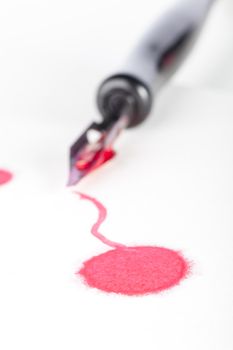 Drop of red ink with calligraphy pen in background