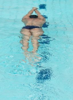 Young male athlete swimming underwater in a swimming pool