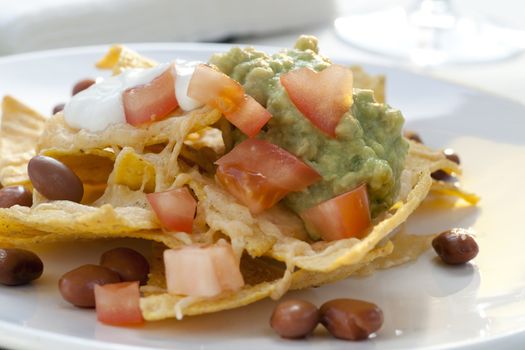 Fresh nacho chips with beans, tomatoes, cheese and guacamole