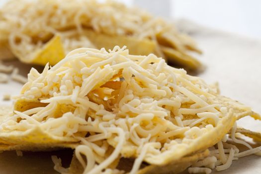 Nacho chips with grated cheese ready for the oven.