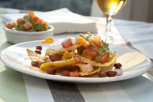 Fresh nacho chips with beans, tomatoes, cheese and guacamole