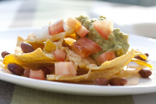 Fresh nacho chips with beans, tomatoes, cheese and guacamole