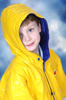 Four year old boy with big blue eyes in a yellow rain coat against a dark blue mottled background. Shot with the Canon 20D.