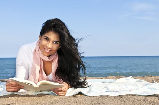 Portrait of beautiful smiling native american girl reading book at beach