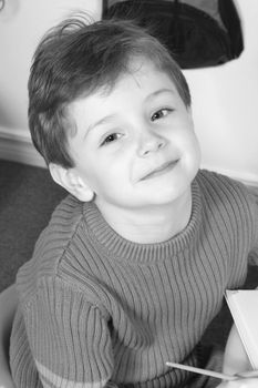 Black & White of a handsome and happy little boy sitting in at a preschool table.  Shot with the Canon 20D.