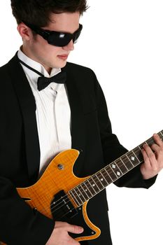 Attractive young man teenager  in tux with electric guitar over white.