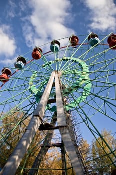 Ferris wheel in an amusement park. Autumn. Against the blue sky.