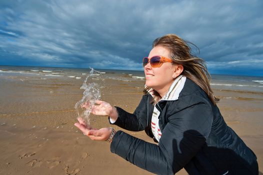 Portrait of mature attractive woman in sunglasses relaxing at the Baltic sea in autumn day.