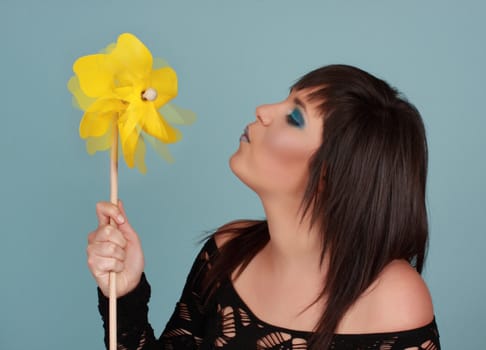 woman blowing a yellow pinwheel