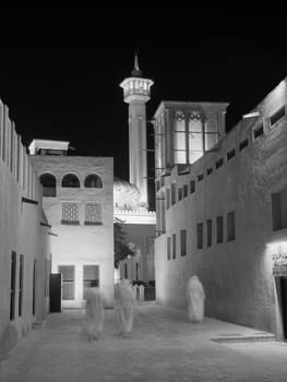 Arab men, in the old merchant quarter of Bastakiya in Dubai, walking to their mosque for evening prayer.