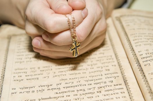 Female hands during reading of a prayer against the orthodox bible 