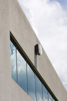 The corner of a concrete office building, with a row of windows reflecting the sky.