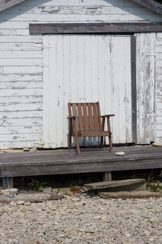 A lone chair outside of a boathouse, where the waterline has not reached for years.  Along the shores of Georgian Bay, in the Bruce Peninsula, Ontario, Canada.
