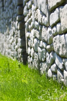An old wall made out of local shore stone, against a carpet of green grass.