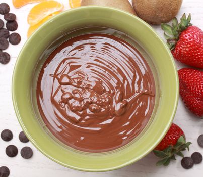 chocolate fondue kit and fresh fruit, beige background