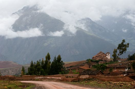 Small village in the Andes. Small structures against the mountains which tops are covered by clouds. 