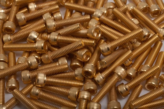 a pile of gold plated screws on white background