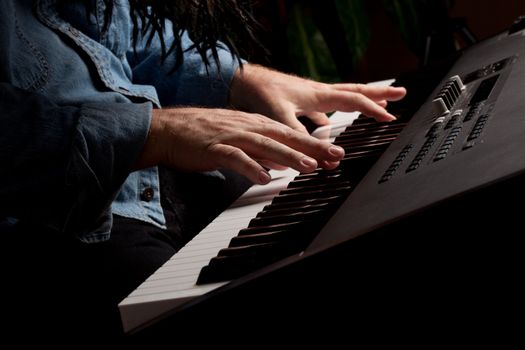 Male Pianist Performs on the Piano Keyboard with Dramatic Lighting.