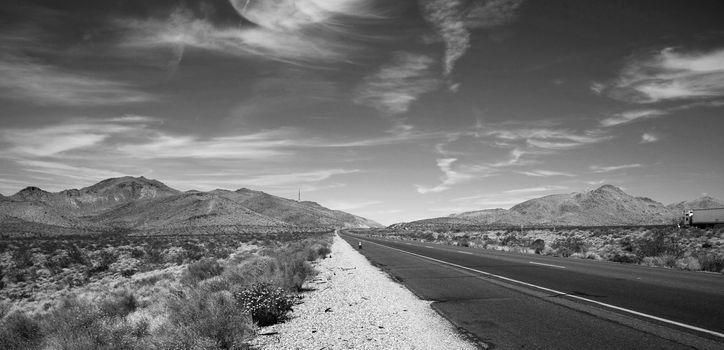 Black and white road with a semi truck heading to the horizon