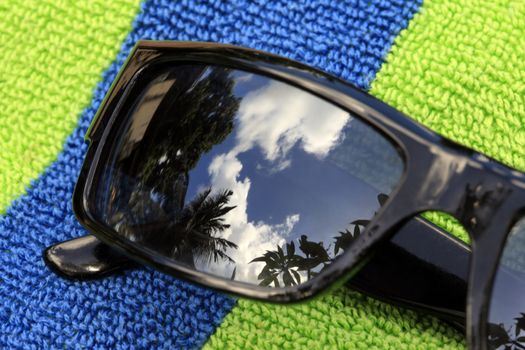 Solar glasses with reflection on a blue-green towel