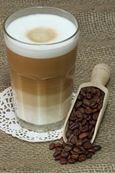 Latte Macchiato in glass with coffee grain on brown background