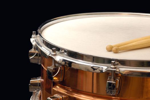 copper snare drum and sticks on black