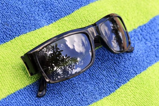 Solar glasses with reflection on a blue-green towel