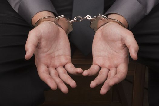 Close-up of hands handcuffed, arrested for questioning.