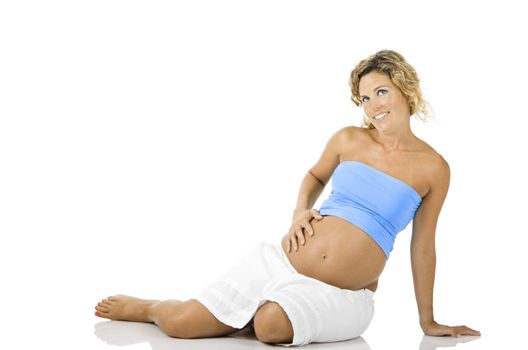 Beautiful pregnant woman seated on the floor and isolated on white background 
