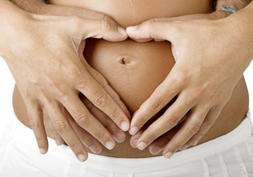 Pregnant women wrap her arms around the belly in the form of the heart. Isolated on white. 