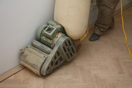 Sanding a new wooden floor with a heavy machine