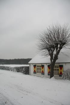 Small cottage in a white grey winter landscape