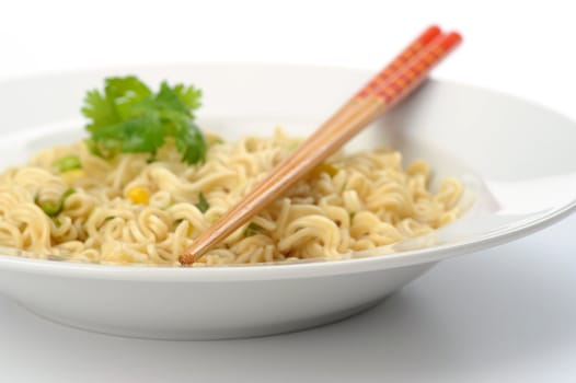 Closeup of chopsticks over a bowl of oriental style noodles.