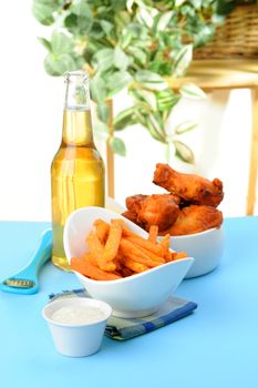 Crispy sweet potato fries served with baked chicken wings and beer.