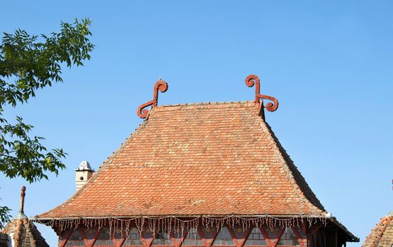 high tiled roof with decorations over blue sky
