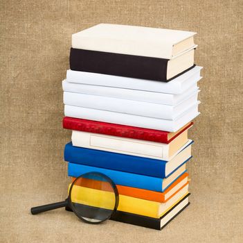 Books and magnifying glass on the fabric background