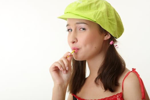 The girl in a green cap eats a sugar candy