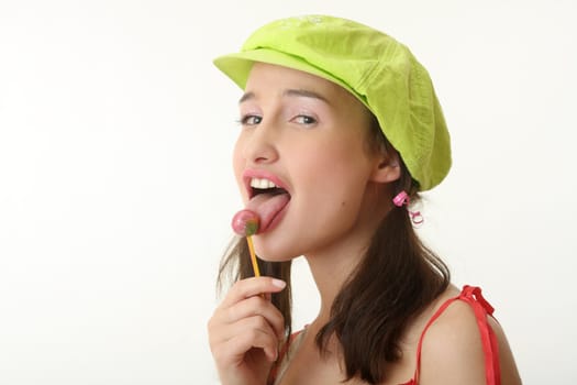 The girl in a green cap eats a sugar candy