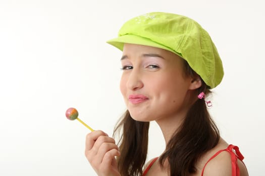 The girl in a green cap eats a sugar candy