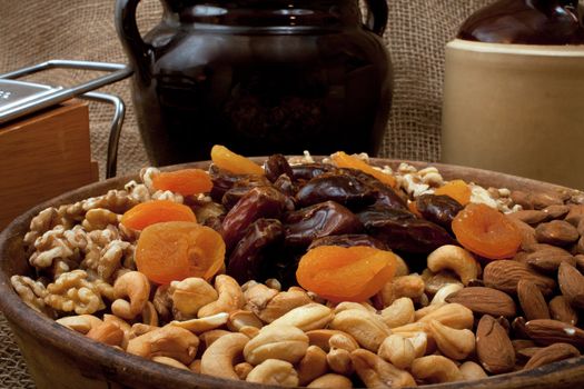 Tray with walnuts, almonds, cashews, dates and apricots in a rustik setting with stoneware