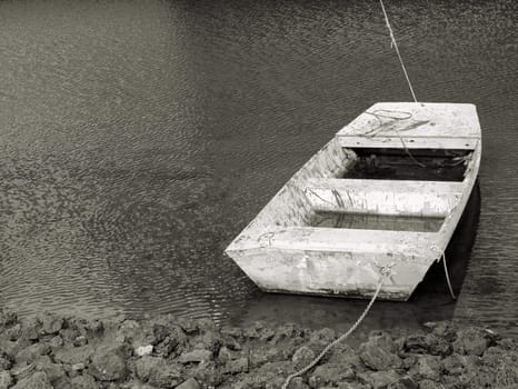 Old boat along the shore in very poor condition shown in black and white