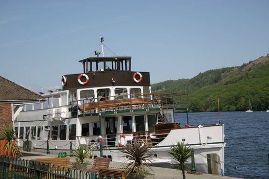 small cruise boat docked at the edge of a lake