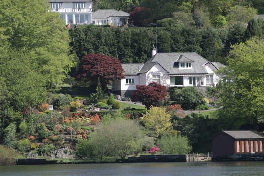 large white house amongst the trees with a beautiful landscape garden